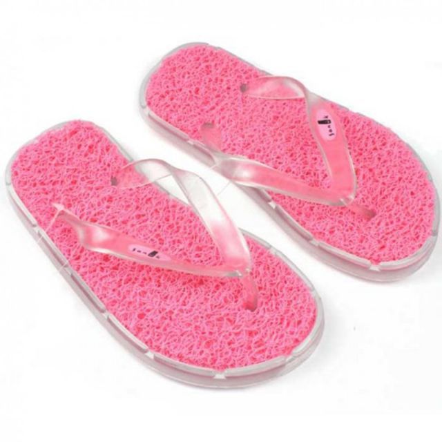 pair of pink flip flops with clear straps and bow detail on the bottom, isolated against white background