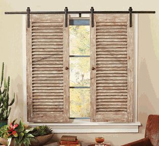 a living room filled with furniture and a window covered in wooden shutters next to a potted plant