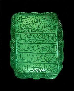 a green glass plaque with arabic writing on it's sides and an inscription in the middle