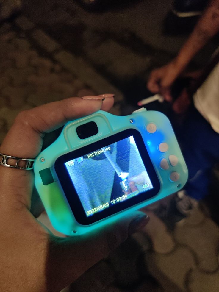 a person is holding a small camera in their hand with the screen showing an image on it