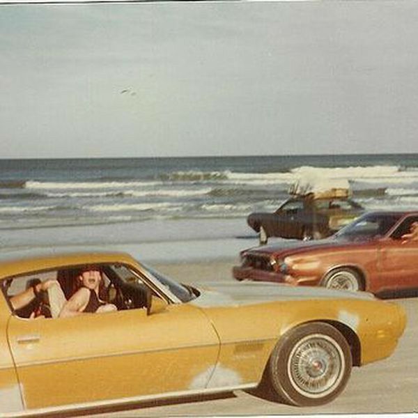 two cars driving on the beach next to each other