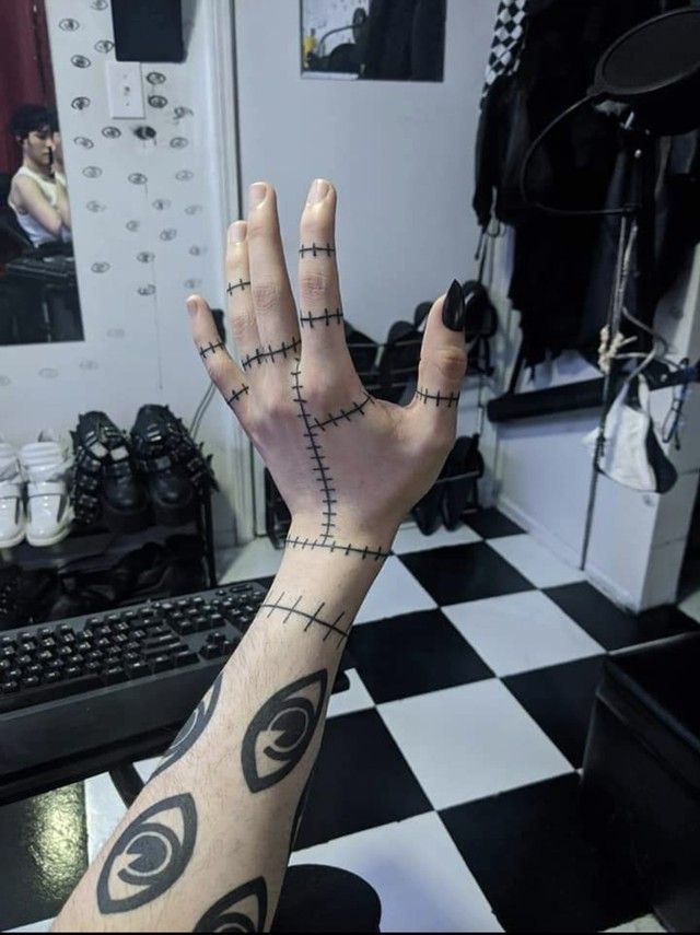 a person with tattoos on their arm and hand in front of a computer desk,