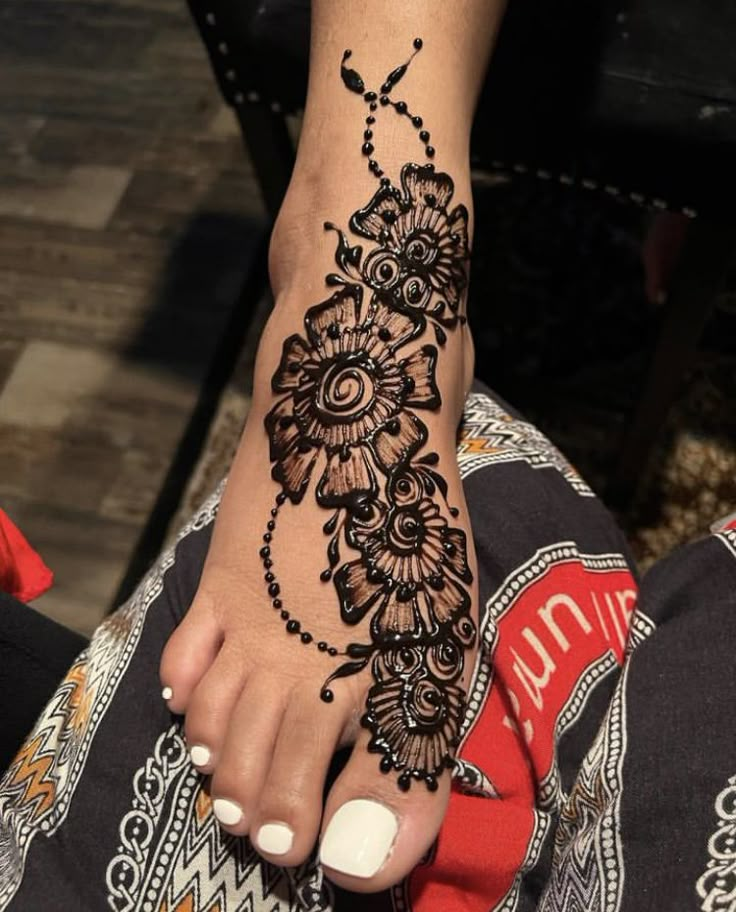 a woman's foot with henna tattoos on it