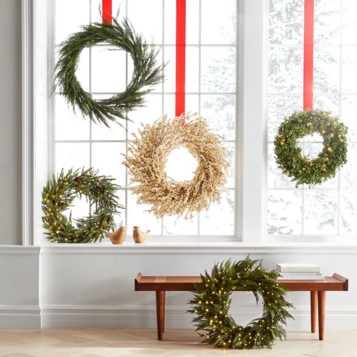 christmas wreaths hanging on the wall next to a window