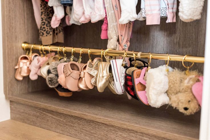 baby shoes are hanging from a rack in a closet with other items on the shelf