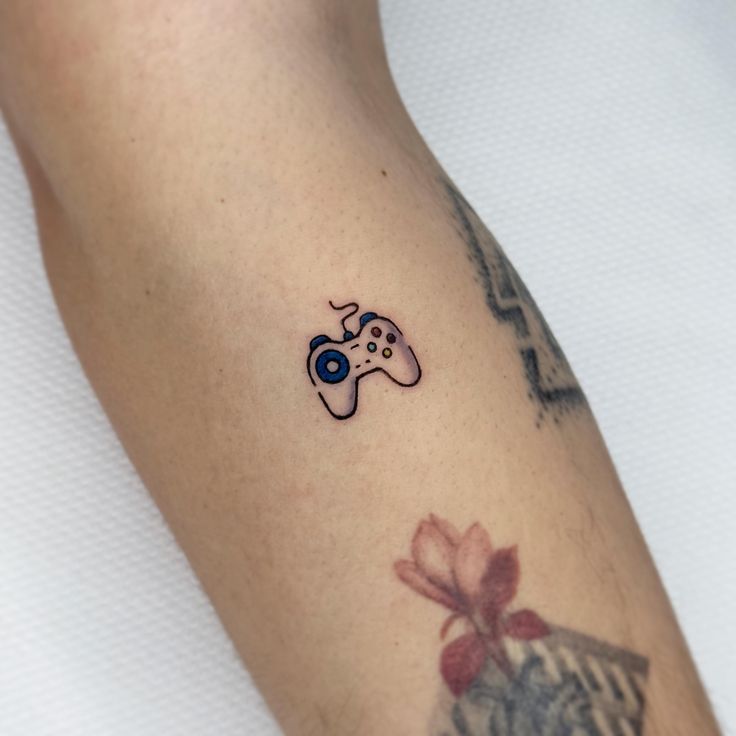 a tattoo with a video game controller on it's left arm and a bow around the wrist