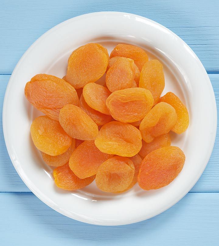 peeled apricots in a white bowl on a blue background