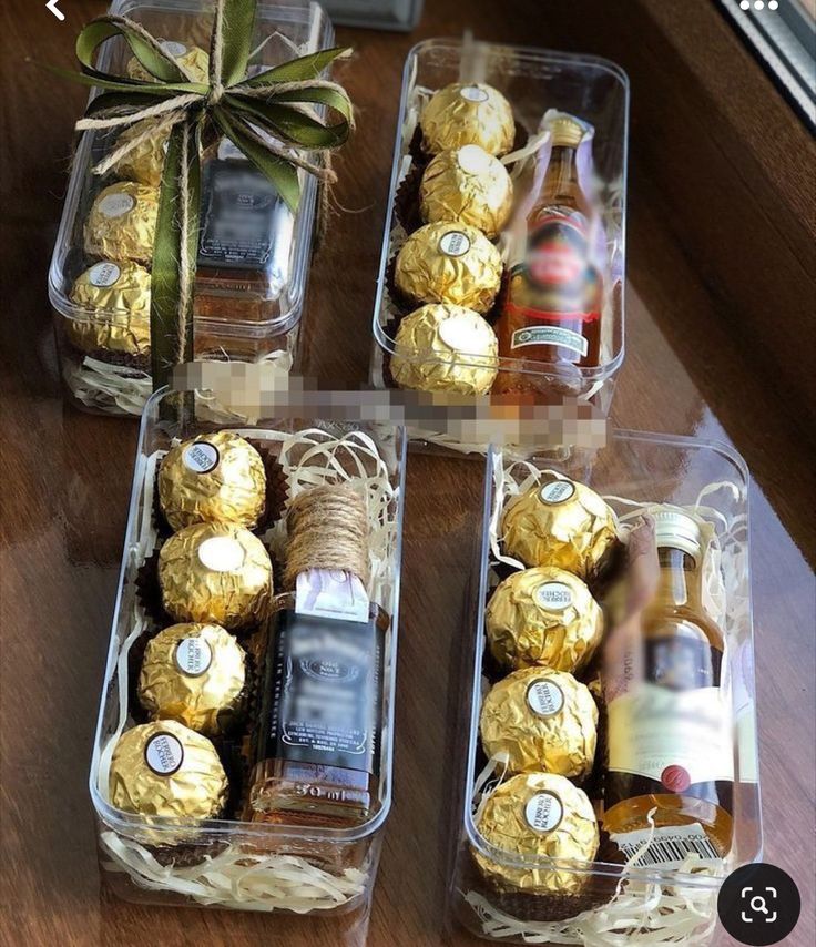 chocolates and liquor in plastic containers on a table next to a glass bottle with a bow