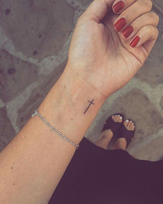 a woman's wrist with a small cross tattoo on the left side of her arm