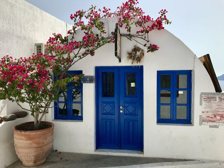 a white house with blue doors and pink flowers