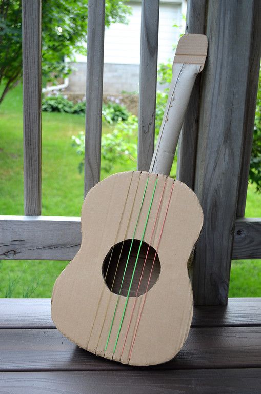 a small wooden guitar sitting on top of a porch next to a fence and grass