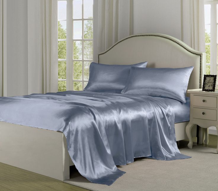 a bed with blue sheets and pillows in a room