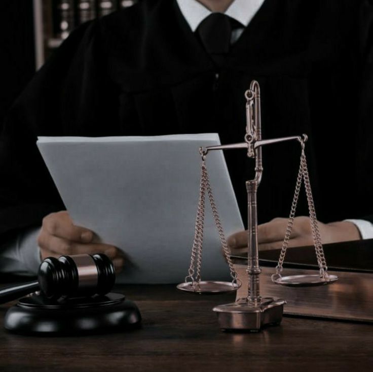 a judge sitting in front of a laptop computer next to a scale and gavel