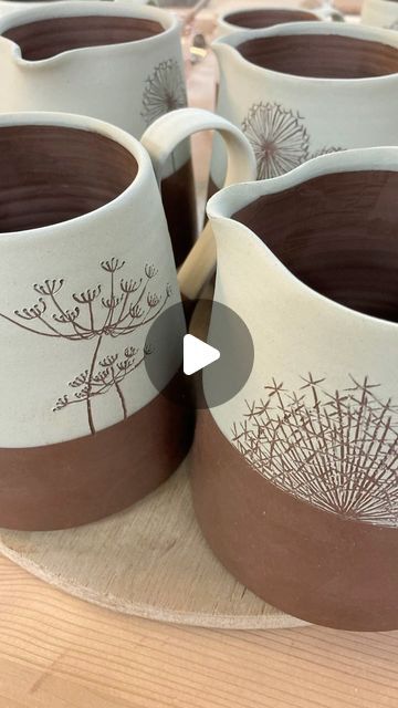 several white and brown coffee mugs sitting on top of a wooden table next to each other