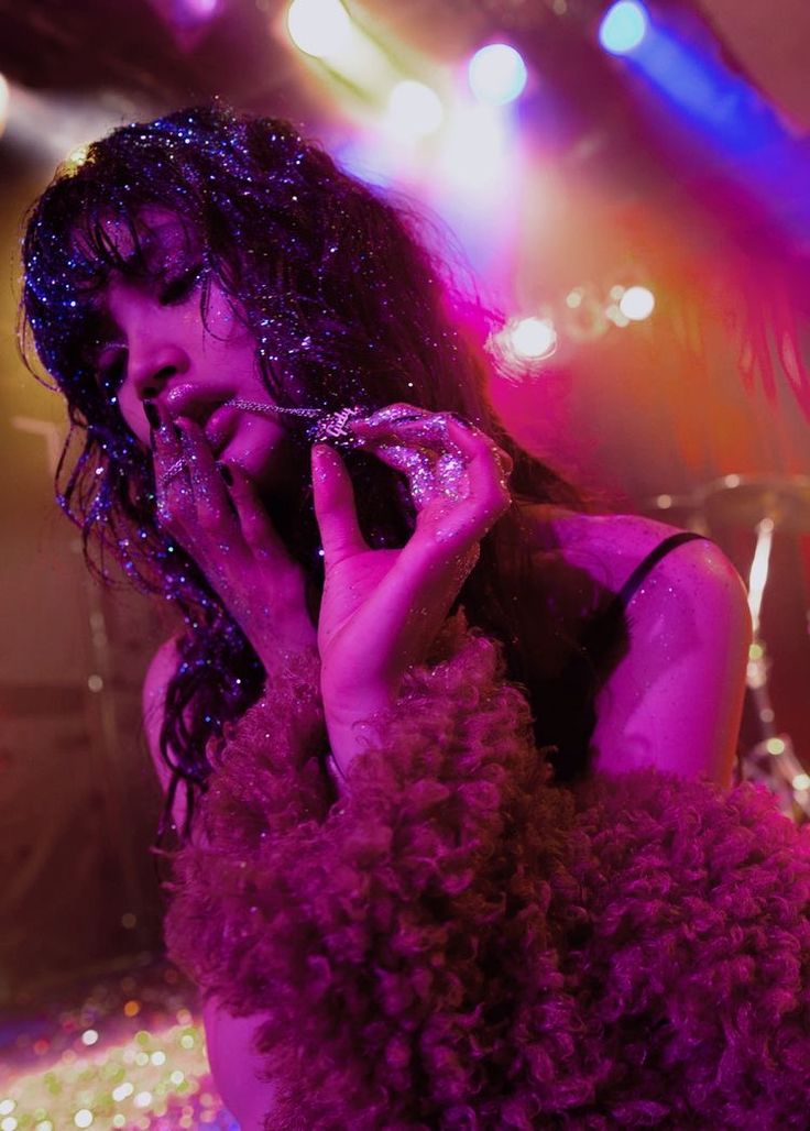 a woman with curly hair is talking on her cell phone while wearing a purple dress