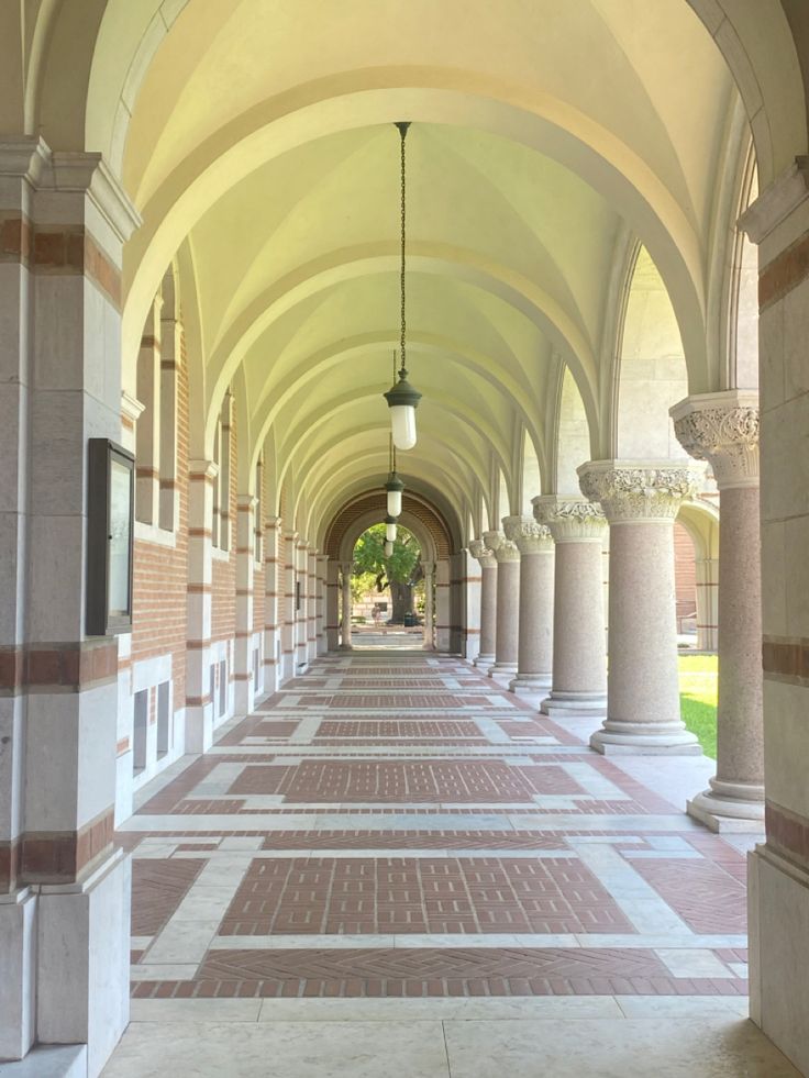 an arched walkway with columns and lamps on either side