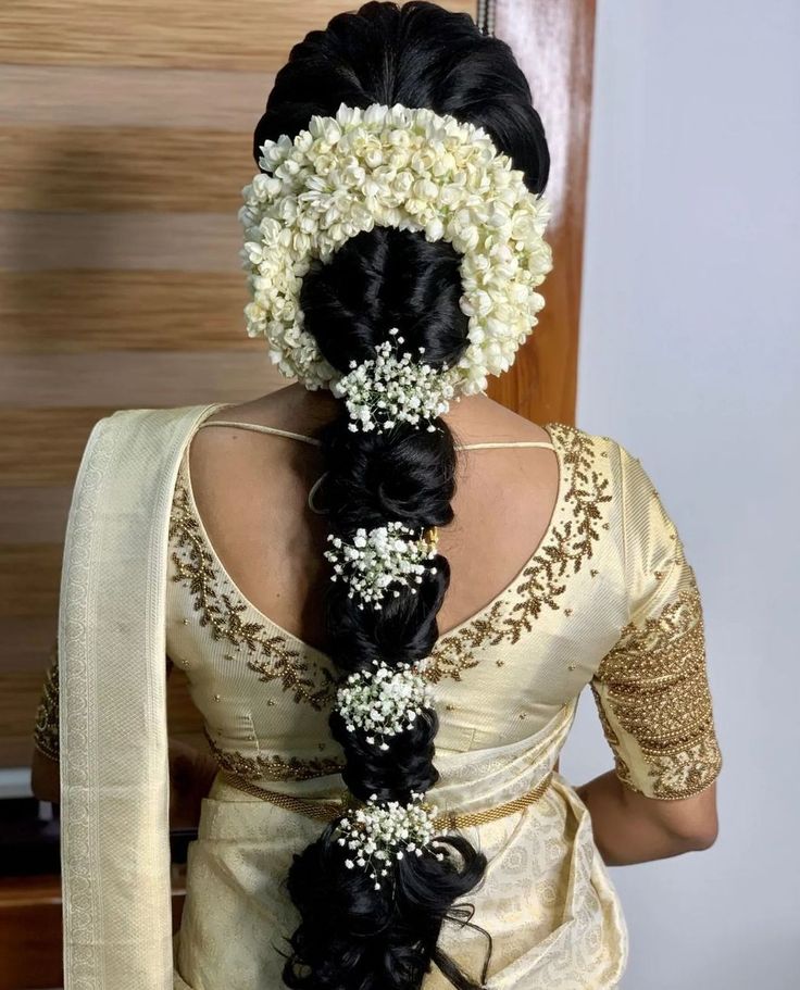 a woman with braids and flowers in her hair is wearing a white sari