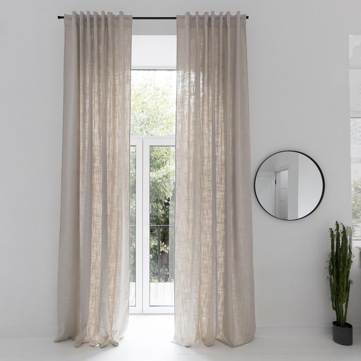 a white room with a mirror and curtains on the window sill next to a potted plant