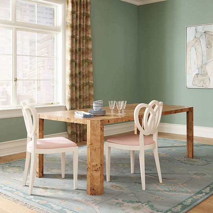 a dining room table with two chairs and a rug