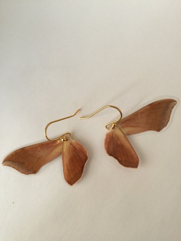 the earrings are made out of wood and have long, thin leaves hanging from them