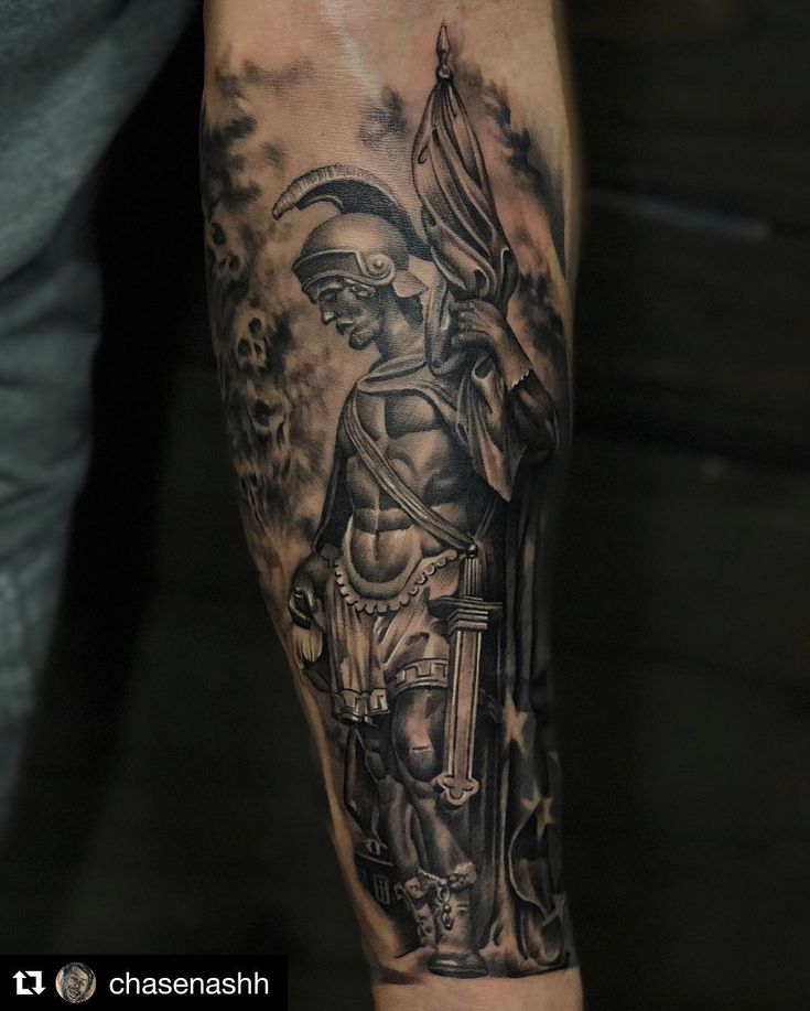 a man's arm with a black and grey tattoo design on the left forearm