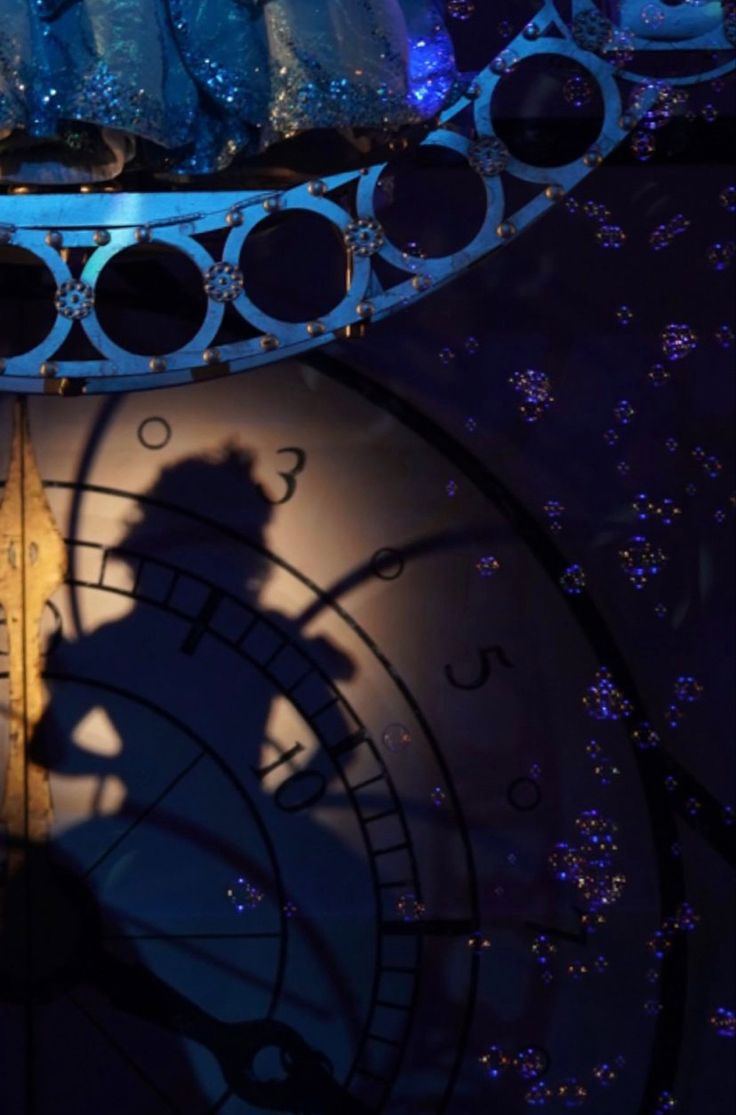 the shadow of a person standing on top of a large clock in front of a stage