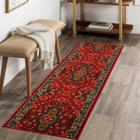 a long red rug in the corner of a room with a wooden table and chair