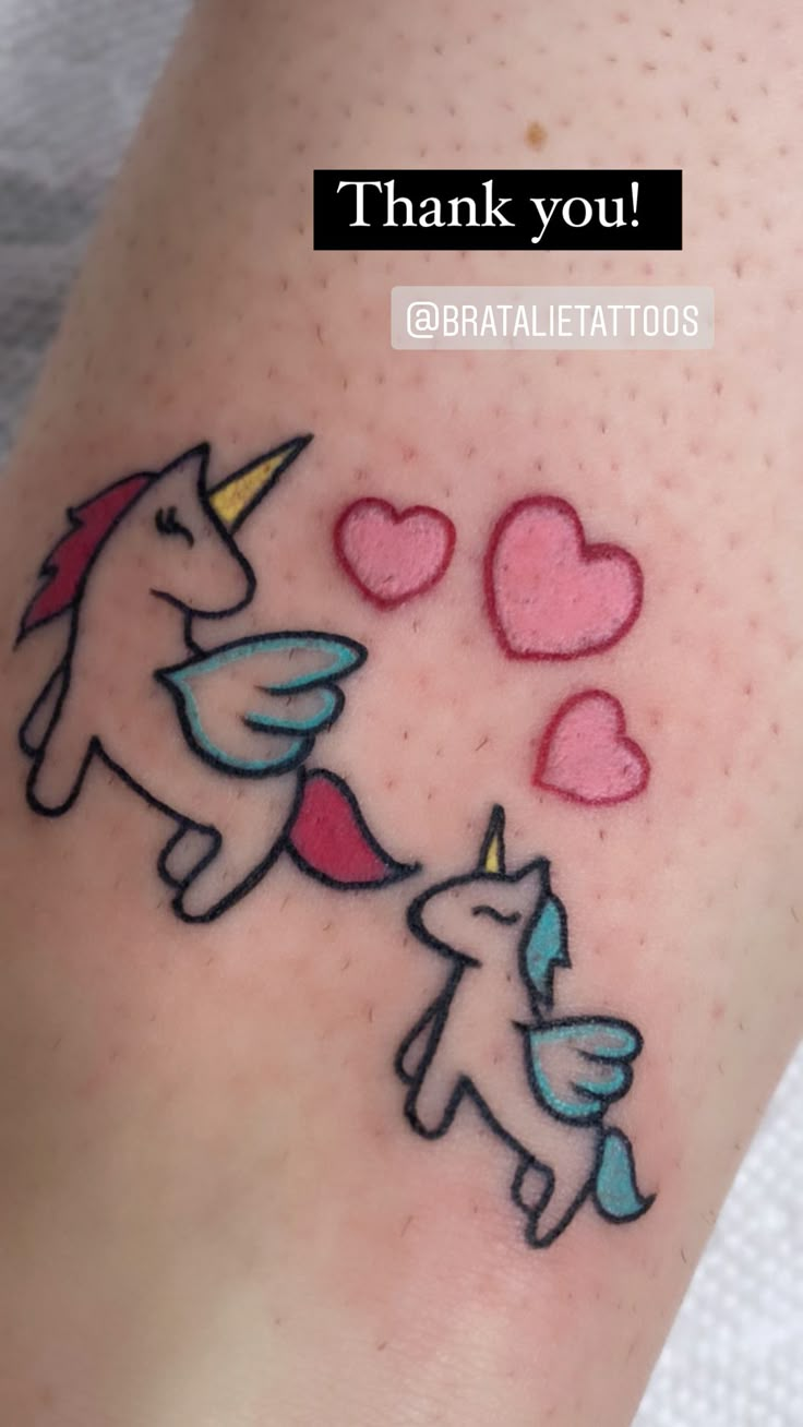 a tattoo with two unicorns and hearts on it