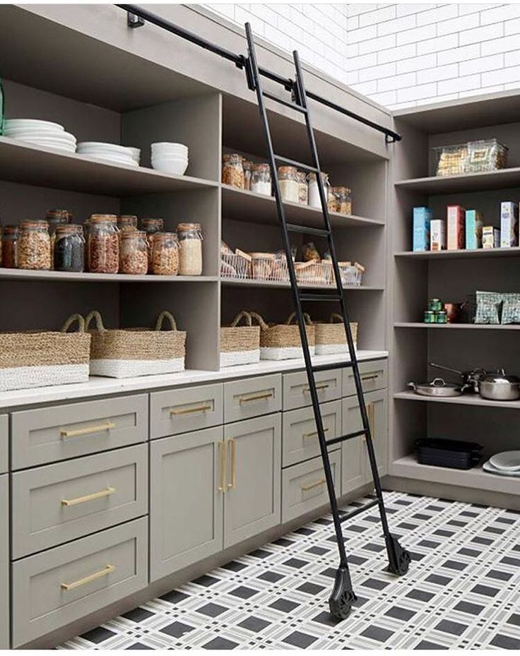 a ladder is in the middle of a kitchen with gray cabinets and white tiles on the floor