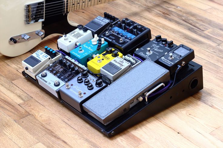 an electronic device sitting on top of a hard wood floor next to a white guitar