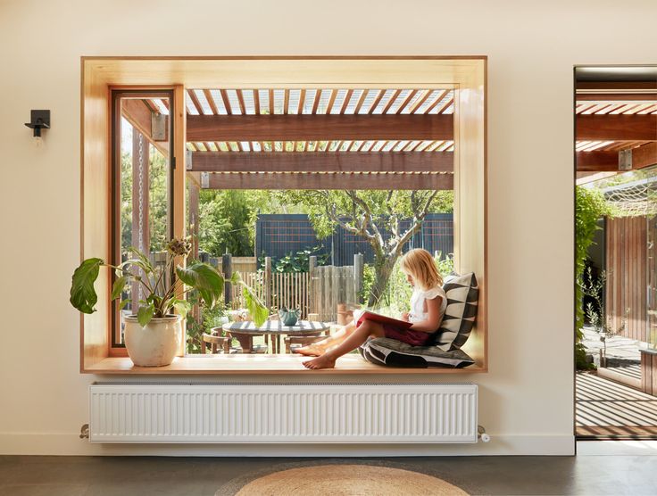 a woman sitting on a window sill reading a book