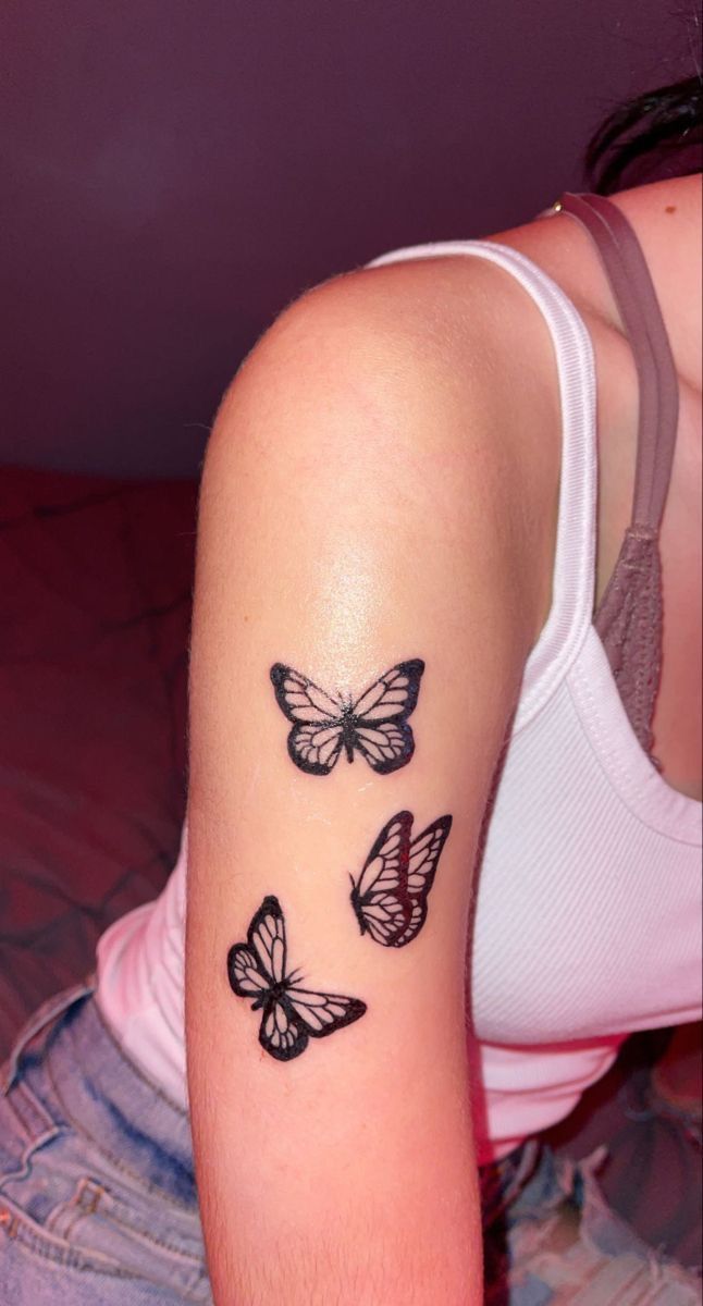 a woman's arm with three butterflies tattooed on the left side of her arm