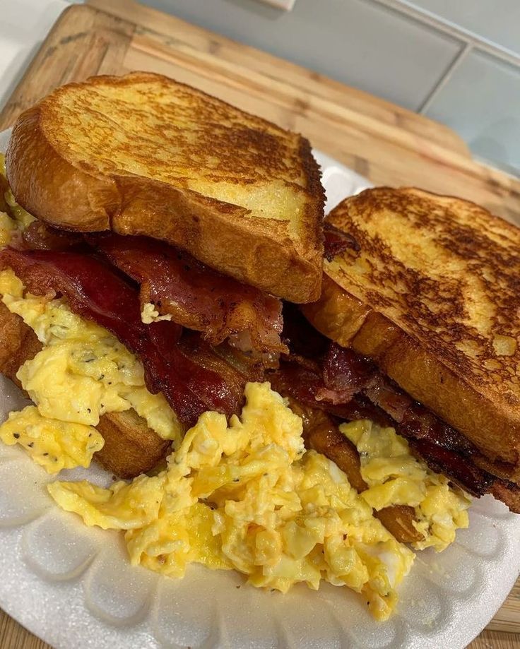 a breakfast sandwich with bacon and eggs on a paper plate