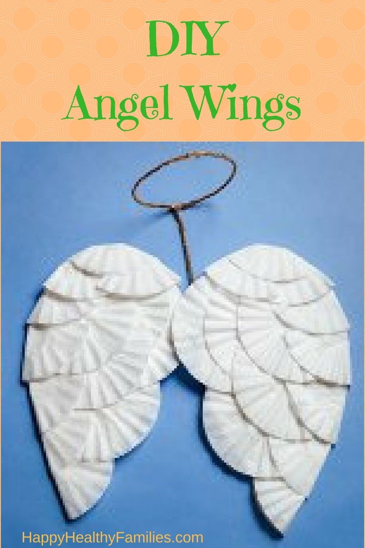 two white paper angel wings hanging from a string on a blue background with a cord in the foreground