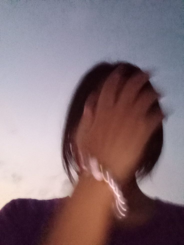 a blurry image of a person holding something in their hand and looking up at the sky