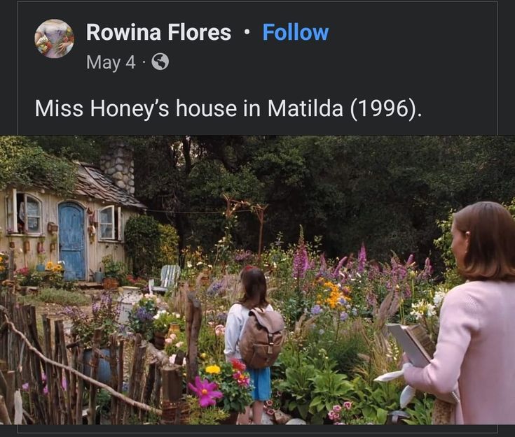 two women standing in front of a garden with flowers and plants growing on the ground