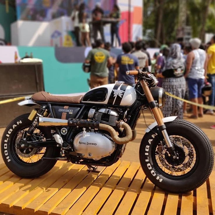 a motorcycle parked on top of a wooden platform in front of a group of people