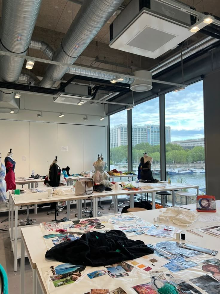 several people are standing in an open room with many tables and clothes on the floor