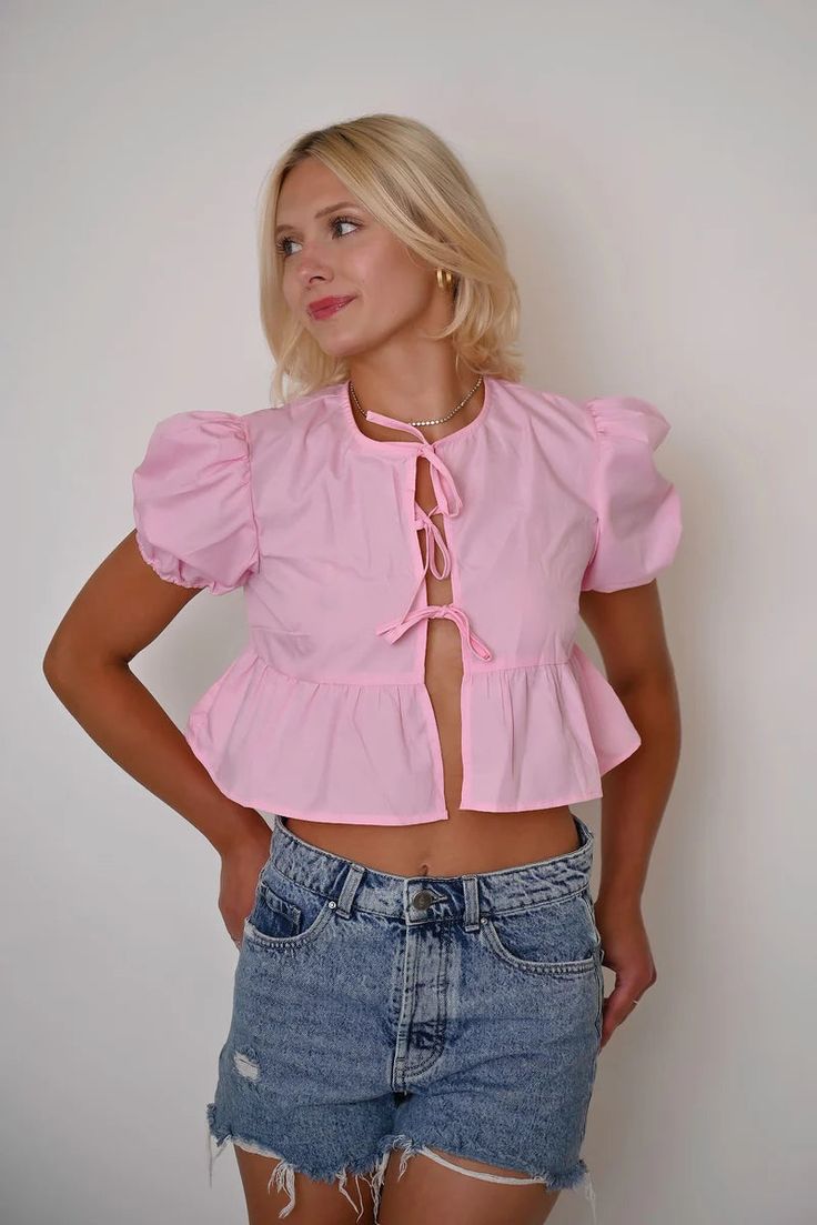 This vibrant pink cropped top combines playful elements with functional design, offering a fresh take on casual wear. Featuring a unique tie-front closure and ruffled details, this piece is perfect for those looking to add a splash of color and whimsy to their wardrobe. Features: Material: Made from a lightweight cotton blend, ensuring comfort and ease of wear. Special Features: This top includes a tie-front design that allows for adjustable fitting and adds a decorative touch. Technical Specifi Pink Cropped Top, Comfy Jumpsuits, Solid Color Sweater, Unique Ties, Sleeveless Short Dress, Splash Of Color, Graduation Outfit, Cropped Style, Puffed Sleeves