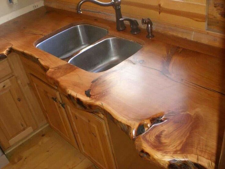 a wooden counter top in a kitchen with stainless steel sink and faucet mounted to it