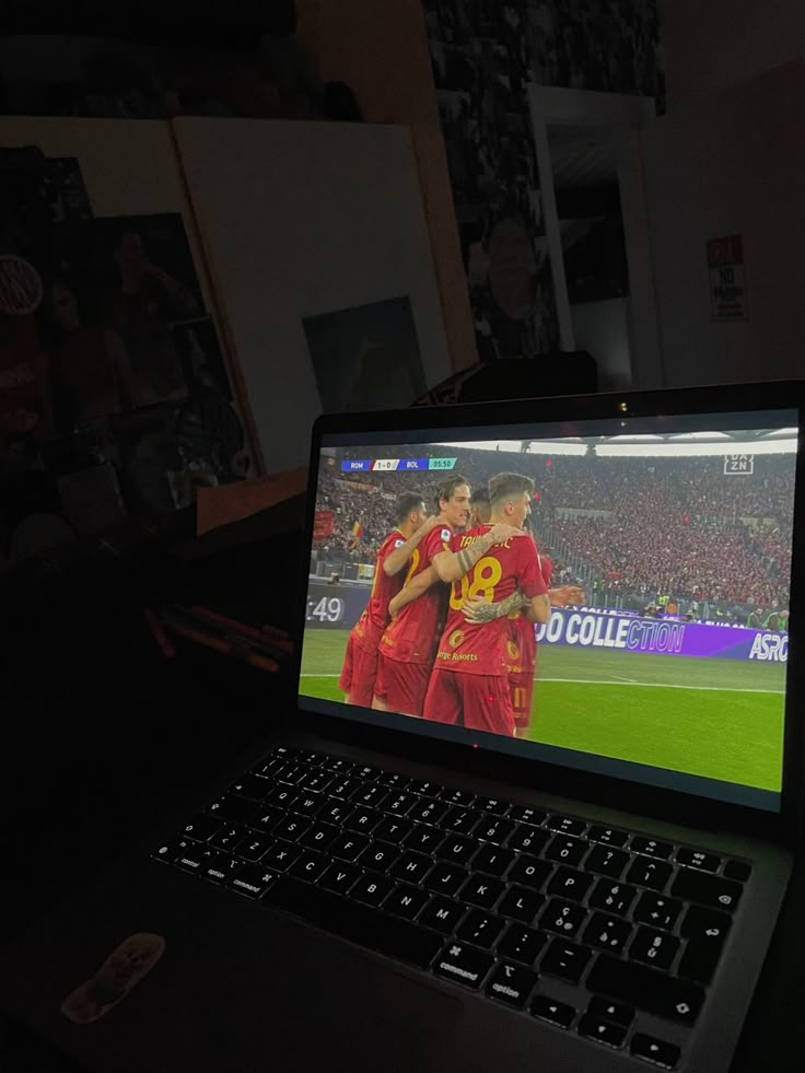 a laptop computer sitting on top of a desk with a soccer game on the screen