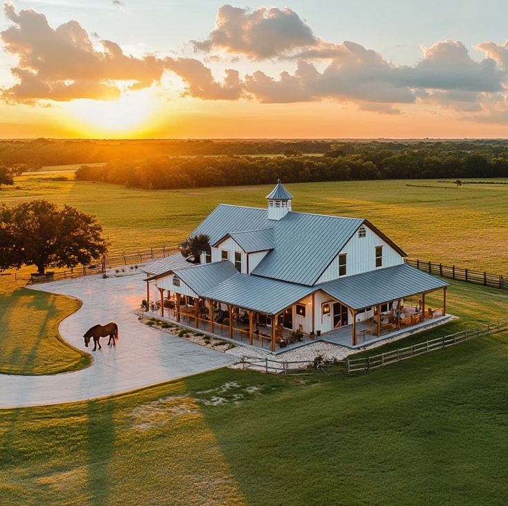 an aerial view of a horse ranch with the sun setting in the background and horses grazing on the grass