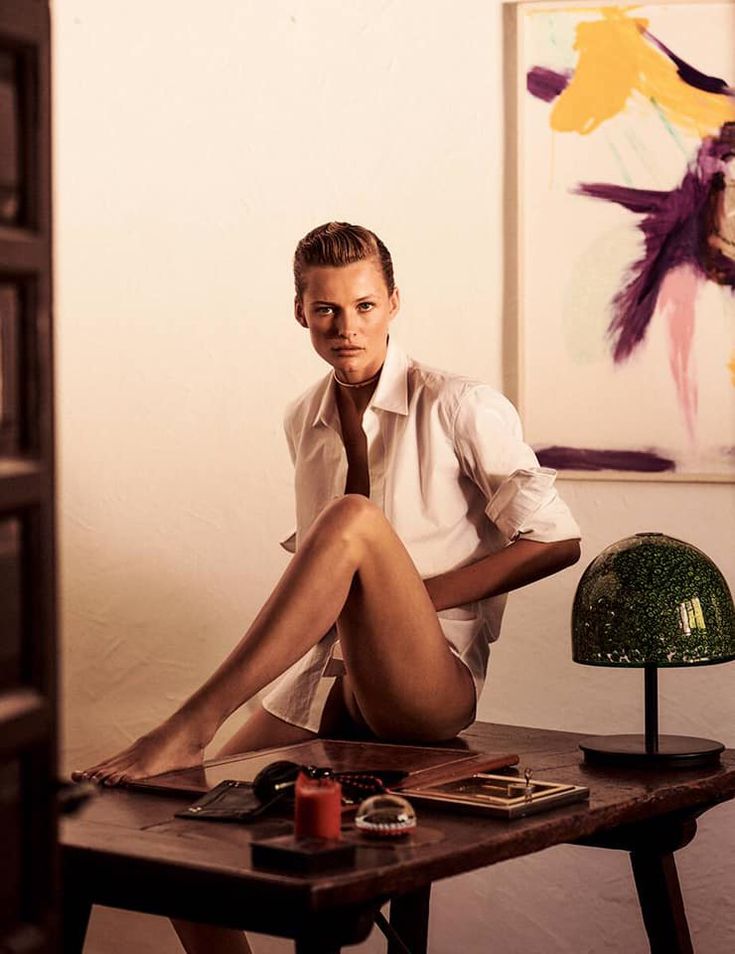 a young man sitting on top of a wooden table next to a lamp and painting