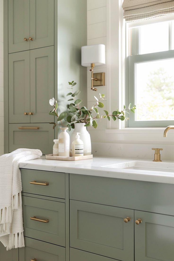 a white sink sitting under a window next to a green cabinet and counter top in a bathroom