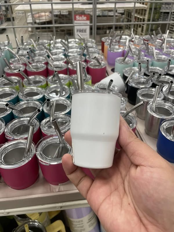 a person is holding an apple in front of many different colored cups and spoons