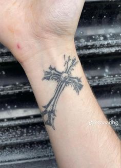 a person with a cross tattoo on their wrist