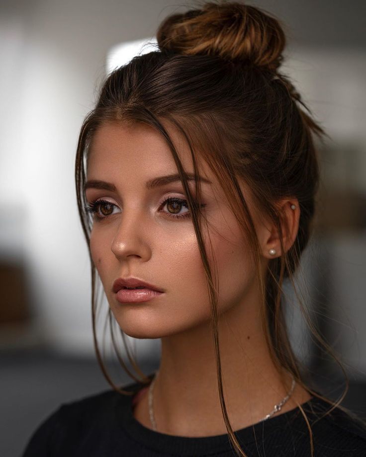 a close up of a person with a hair in a bun and wearing a black shirt