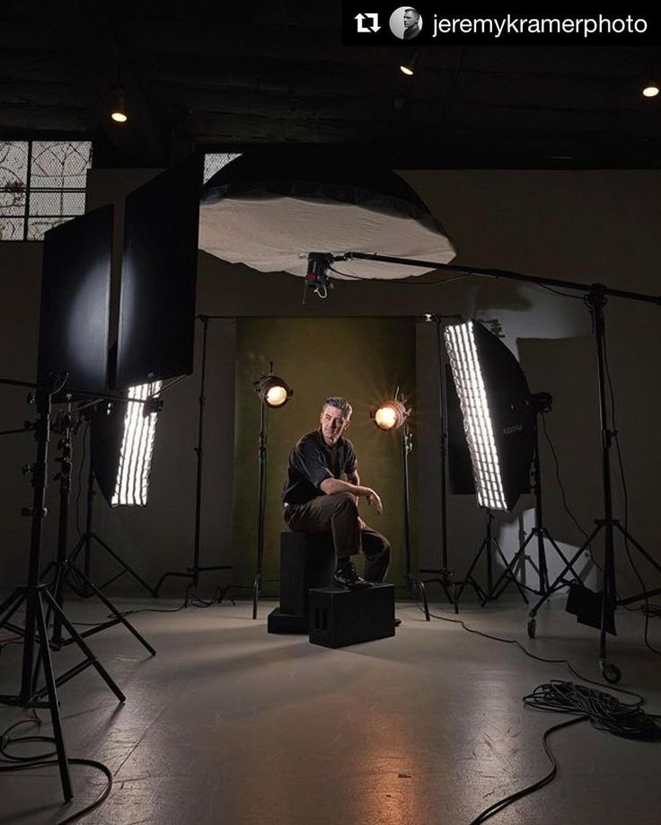 a man sitting on a chair in front of several lights and lighting equipment set up