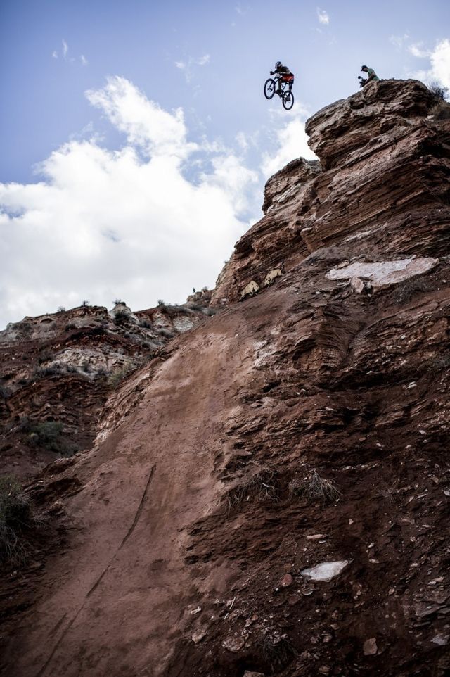 a man riding a bike up the side of a rocky cliff on top of a dirt hill