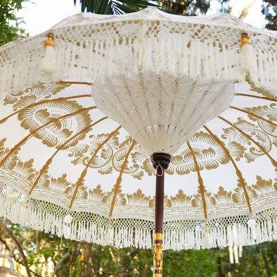 an open umbrella with tassels hanging from it's sides in front of trees